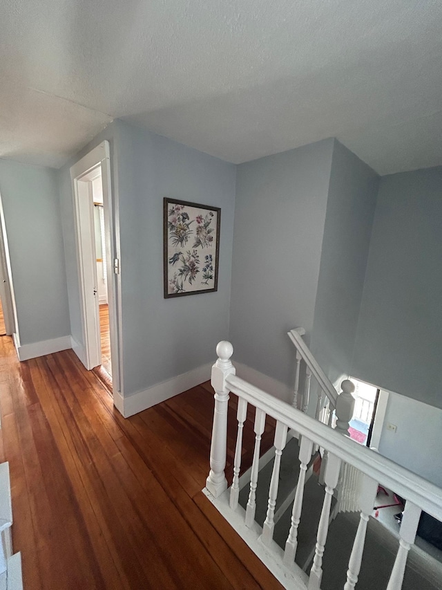 stairs with a textured ceiling, wood-type flooring, and baseboards