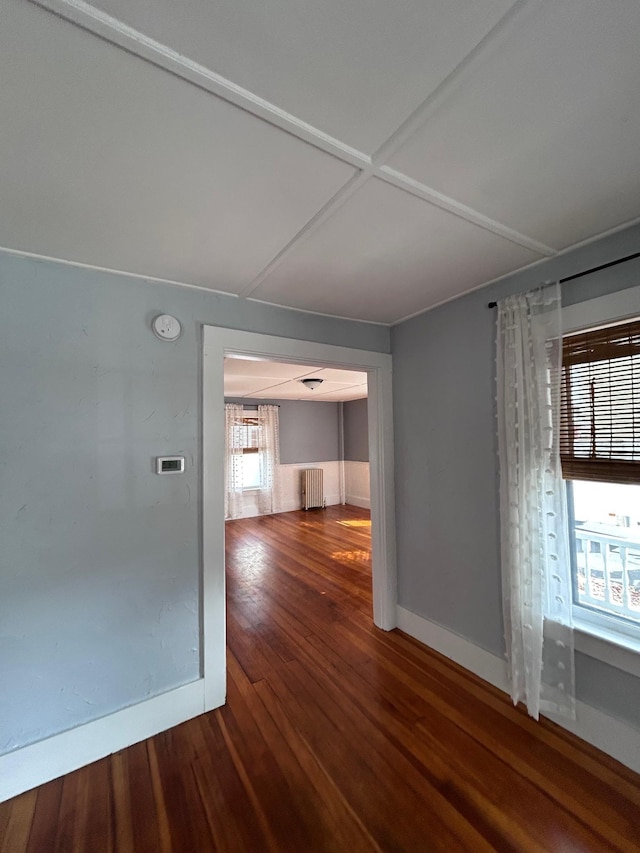 unfurnished room featuring radiator, baseboards, and wood finished floors