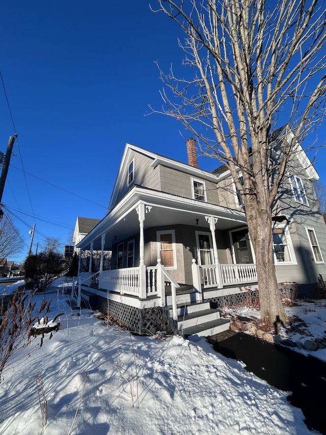 view of front of house featuring covered porch and a chimney