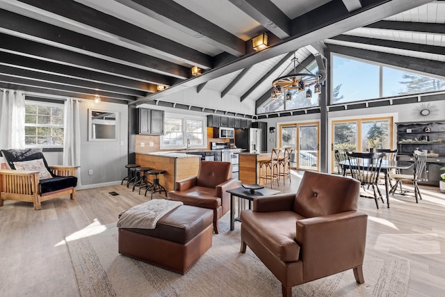 living room featuring a wealth of natural light, light wood-type flooring, and beam ceiling