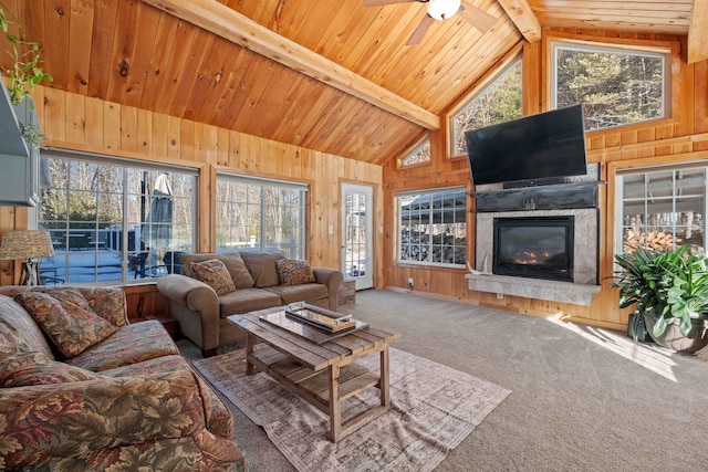 living room with wood walls, wood ceiling, carpet floors, beam ceiling, and a glass covered fireplace