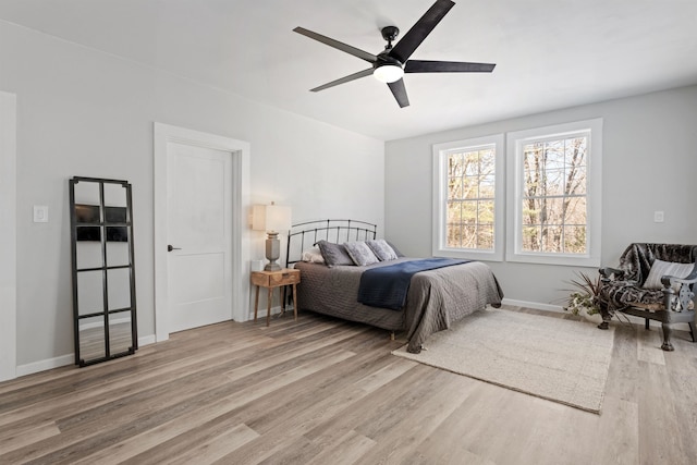 bedroom featuring baseboards, wood finished floors, and a ceiling fan