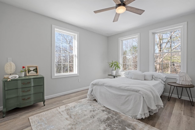 bedroom with a ceiling fan, baseboards, and wood finished floors