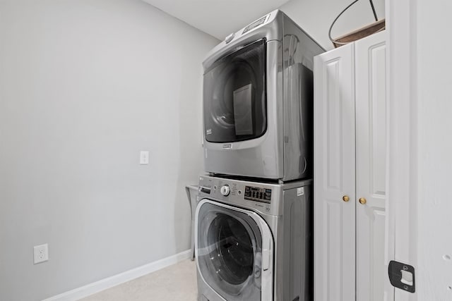 washroom with cabinet space, baseboards, and stacked washer / drying machine