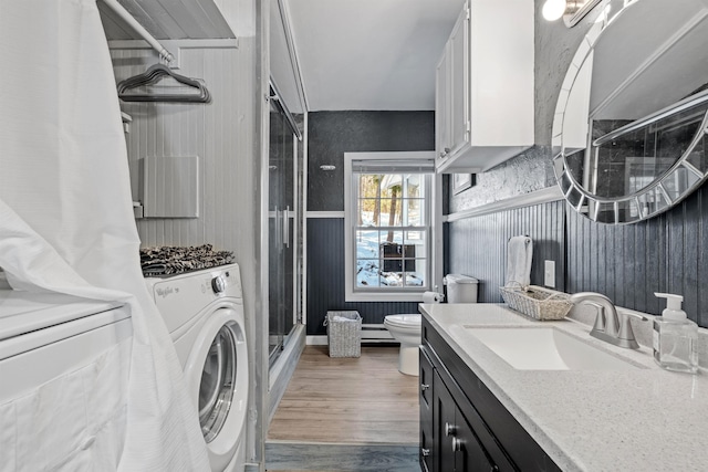 washroom with laundry area, separate washer and dryer, wood finished floors, and a sink