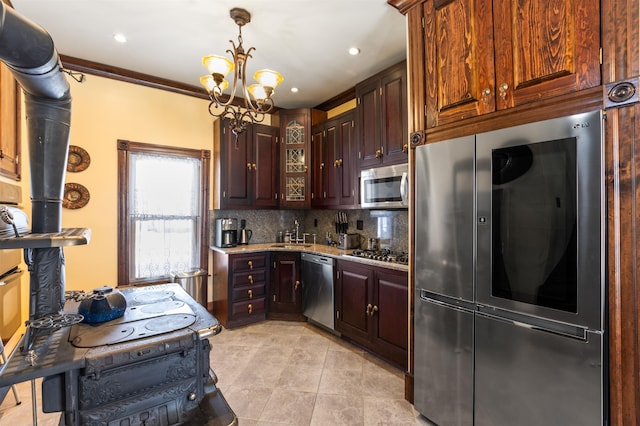 kitchen with decorative backsplash, appliances with stainless steel finishes, an inviting chandelier, pendant lighting, and a sink