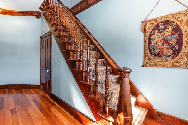 staircase with baseboards and wood finished floors