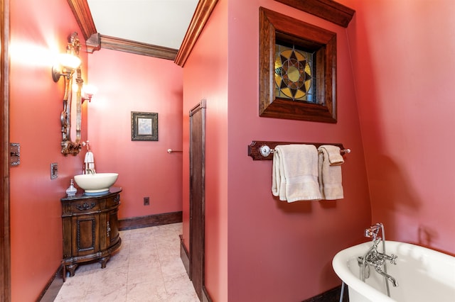 bathroom featuring ornamental molding, a soaking tub, vanity, and baseboards