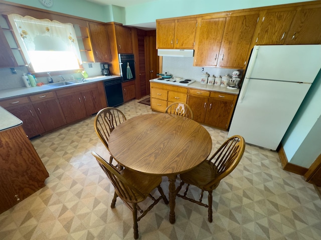 kitchen featuring extractor fan, light floors, brown cabinetry, black appliances, and a sink