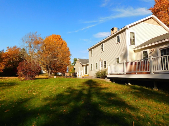 exterior space featuring a deck, a lawn, and a chimney