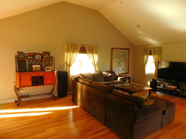 living room featuring light wood-style floors, baseboards, and high vaulted ceiling