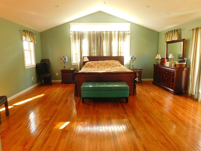 bedroom with vaulted ceiling, hardwood / wood-style floors, and baseboards