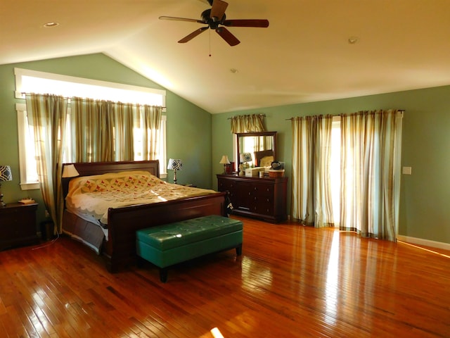 bedroom with vaulted ceiling, multiple windows, and hardwood / wood-style flooring