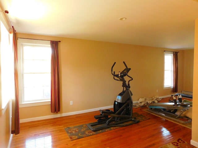 exercise area featuring hardwood / wood-style flooring, a baseboard radiator, and baseboards