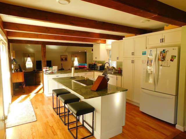 kitchen featuring white appliances, white cabinets, a peninsula, light wood-type flooring, and beam ceiling