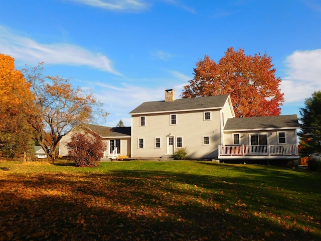 back of house featuring a chimney, a deck, and a yard