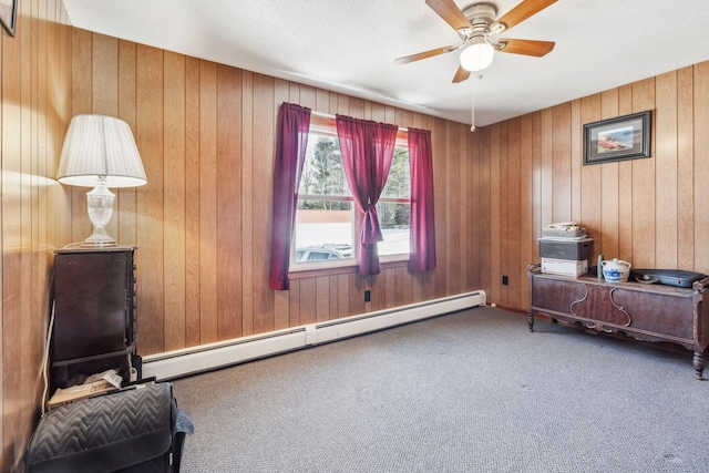 living area featuring a baseboard heating unit, wood walls, carpet flooring, and a ceiling fan