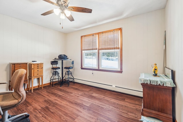 office area featuring a baseboard heating unit, ceiling fan, and wood finished floors