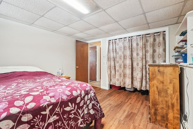 bedroom featuring washer / dryer, a paneled ceiling, baseboards, and wood finished floors