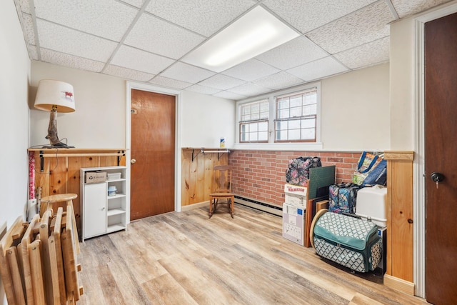 interior space featuring a paneled ceiling, a wainscoted wall, and wood finished floors