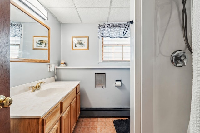 bathroom with a paneled ceiling, vanity, a baseboard heating unit, and tile patterned floors