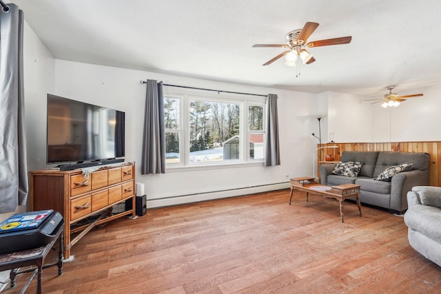 living area featuring a baseboard heating unit, light wood-type flooring, and a ceiling fan