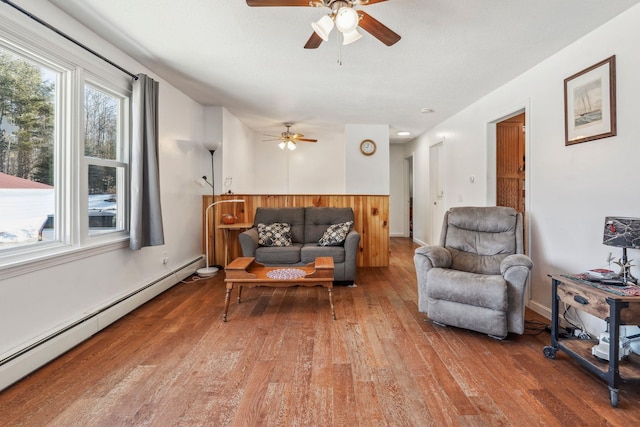 living area featuring a baseboard heating unit, wood-type flooring, and ceiling fan