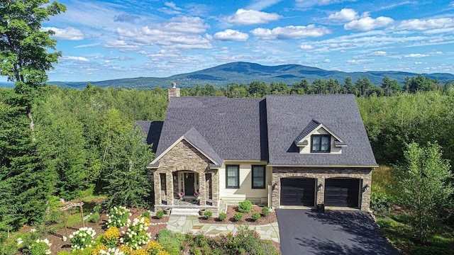 view of front of property featuring stone siding, aphalt driveway, an attached garage, and a mountain view