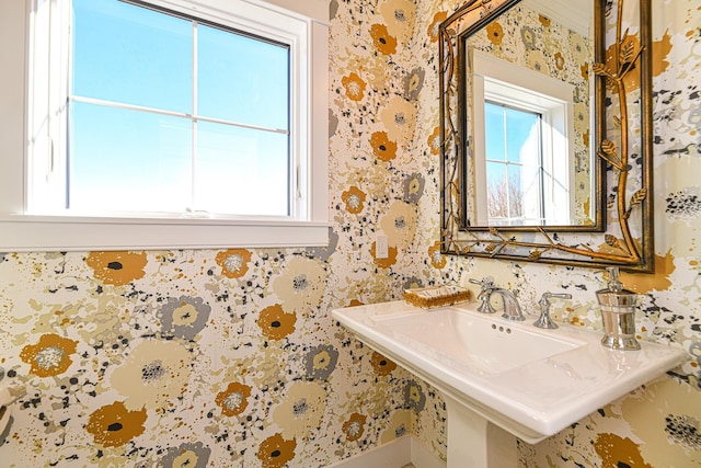 bathroom with wallpapered walls and a sink