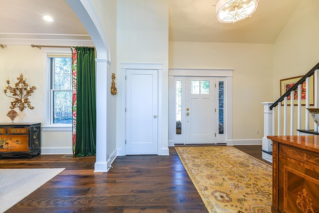 entrance foyer with arched walkways, stairway, wood finished floors, and baseboards