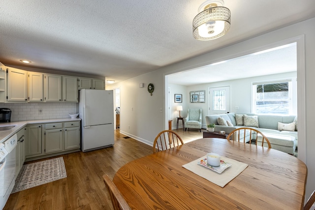 dining room with a textured ceiling, dark wood-type flooring, and baseboards