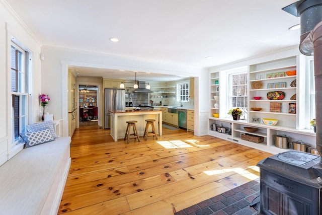 interior space with appliances with stainless steel finishes, light wood-style flooring, wall chimney exhaust hood, and open shelves