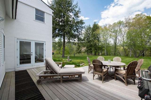 deck with outdoor dining space, french doors, and a lawn