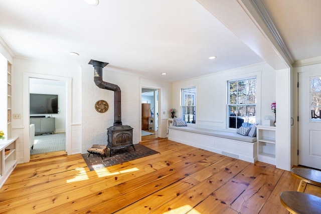 living room with a wood stove, visible vents, hardwood / wood-style floors, and ornamental molding