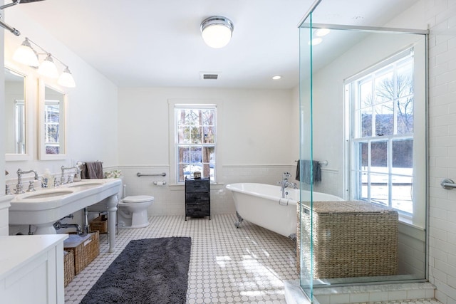 bathroom featuring visible vents, a stall shower, wainscoting, tile patterned flooring, and a freestanding tub