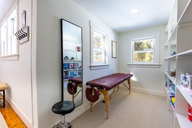 recreation room featuring light carpet and baseboards