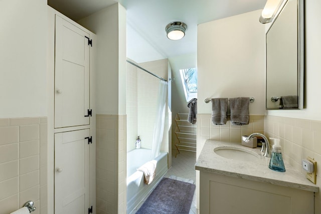 full bath featuring wainscoting, tile patterned flooring, shower / bath combination with curtain, vanity, and tile walls