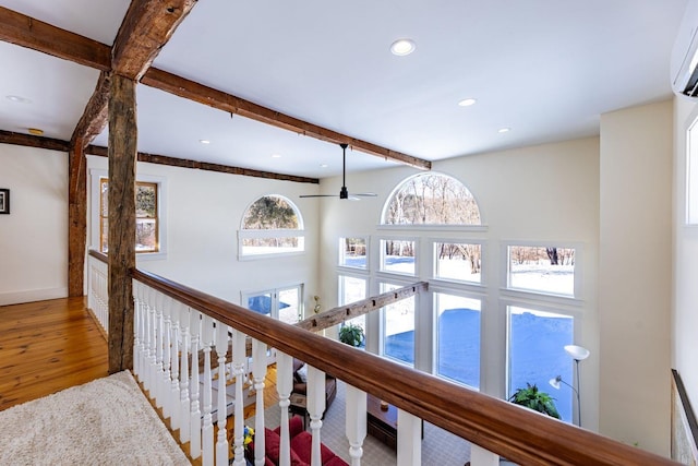 hallway with recessed lighting, a wall mounted AC, wood finished floors, beamed ceiling, and baseboards