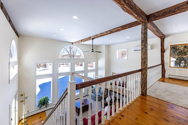 corridor with beam ceiling, an AC wall unit, an upstairs landing, and hardwood / wood-style floors