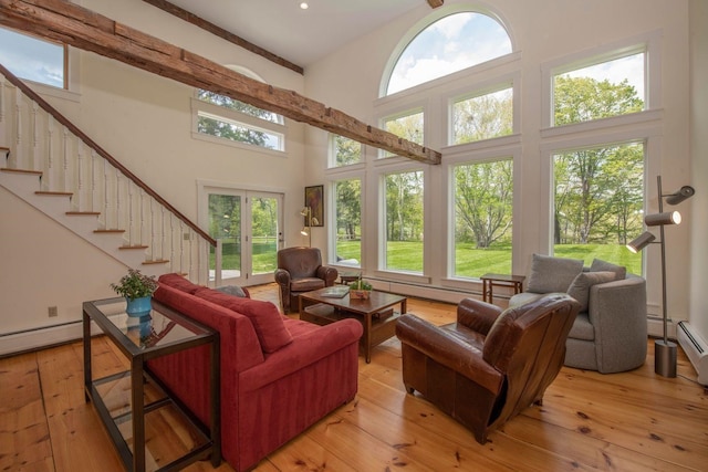 living room featuring a wealth of natural light, a high ceiling, light wood finished floors, and stairs