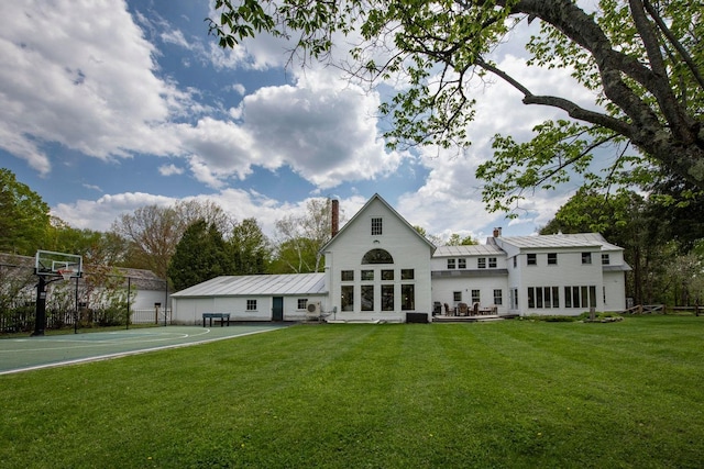 rear view of property with basketball court, a lawn, and a chimney