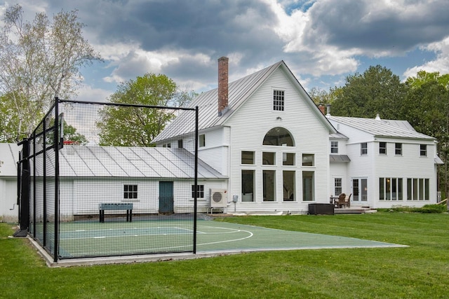 rear view of property with basketball hoop, metal roof, a yard, a standing seam roof, and a chimney