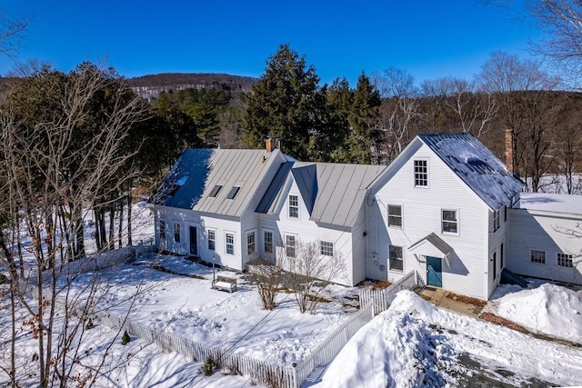 view of front of home featuring entry steps, a chimney, fence, and a standing seam roof