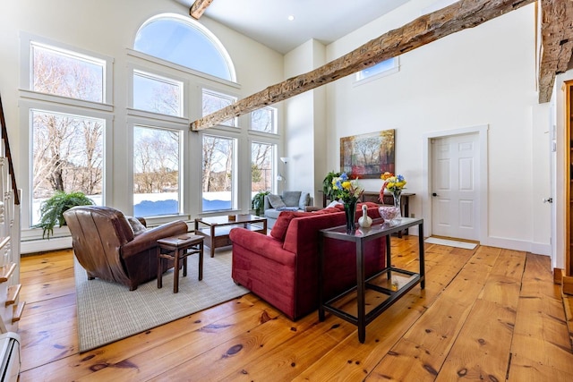 living room featuring a high ceiling, baseboard heating, and light wood-style flooring