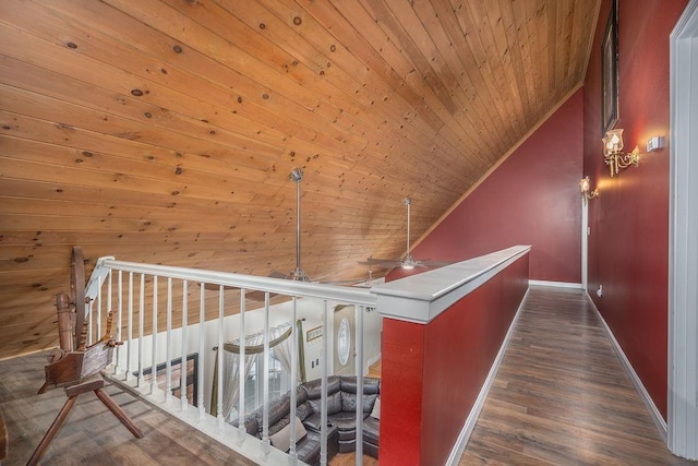 corridor featuring baseboards, lofted ceiling, wooden ceiling, wood finished floors, and an upstairs landing