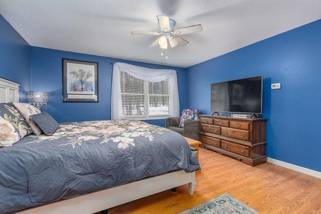 bedroom with a textured ceiling, ceiling fan, wood finished floors, and baseboards