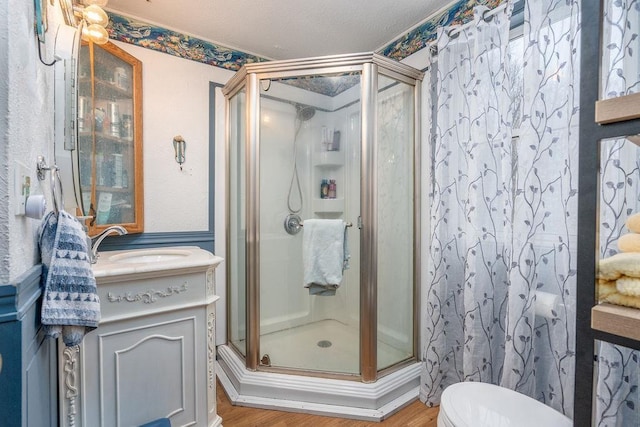 full bathroom featuring a stall shower, vanity, toilet, and wood finished floors