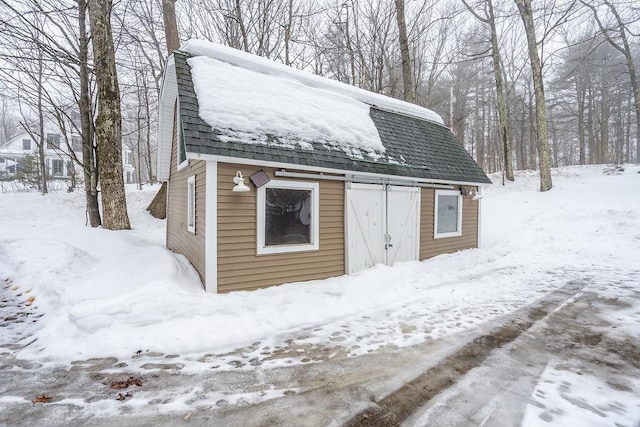 snow covered structure featuring an outbuilding and a barn