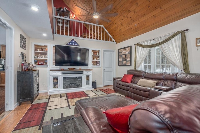 living room with ceiling fan, built in shelves, wooden ceiling, a fireplace, and wood finished floors