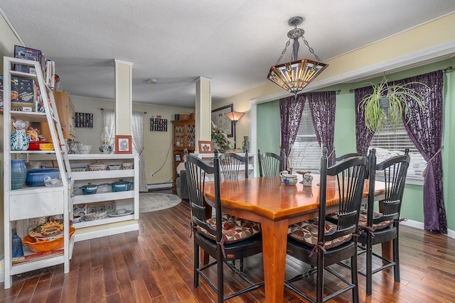 dining space with a baseboard radiator, a textured ceiling, and wood finished floors